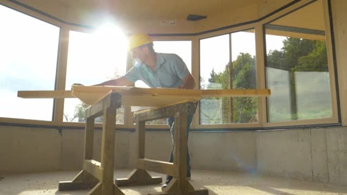 镜头耀斑: 木匠测量一块木板，并将测量结果与他的计划进行比较。