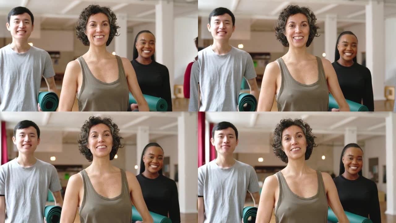 微笑的男人和女人拿着瑜伽垫站在一起上瑜伽课