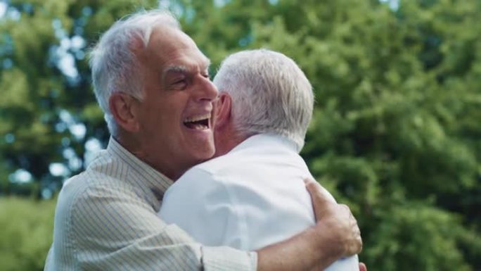 一位富有表现力的老人在绿色公园的一次情感聚会中与他的老朋友见面。两名年长的兄弟拥抱并表达了他们的激动