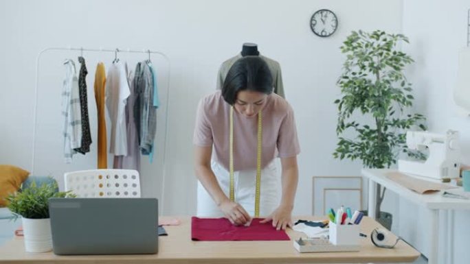亚洲女裁缝的慢动作用布和粉笔制作新的现代服装