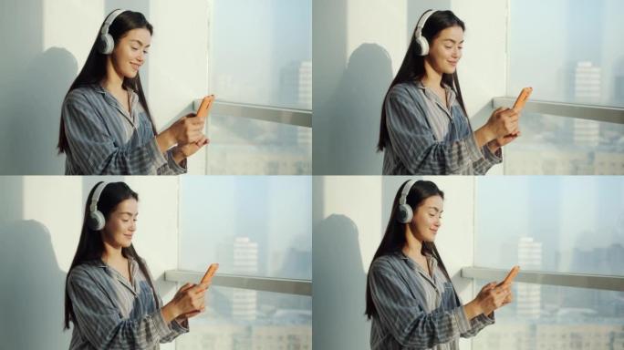 漂亮的亚洲女孩在家里用智能手机和耳机听音乐