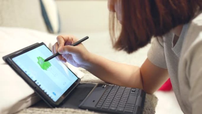 女人在晚上在家中使用数字铅笔并在数字平板电脑上绘画