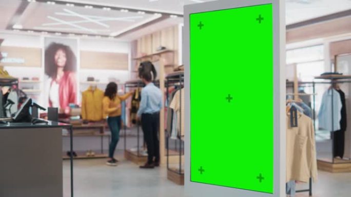 客户在服装店购物时使用带有绿屏色度键模型的落地式液晶触摸显示器。她正在检查信息，查看平面图，在线选择