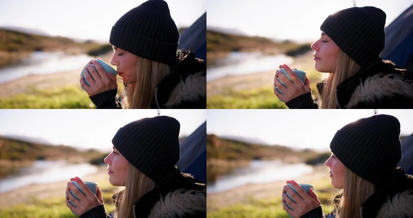 4k视频片段，一名年轻女子在露营旅行中坐着喝杯咖啡