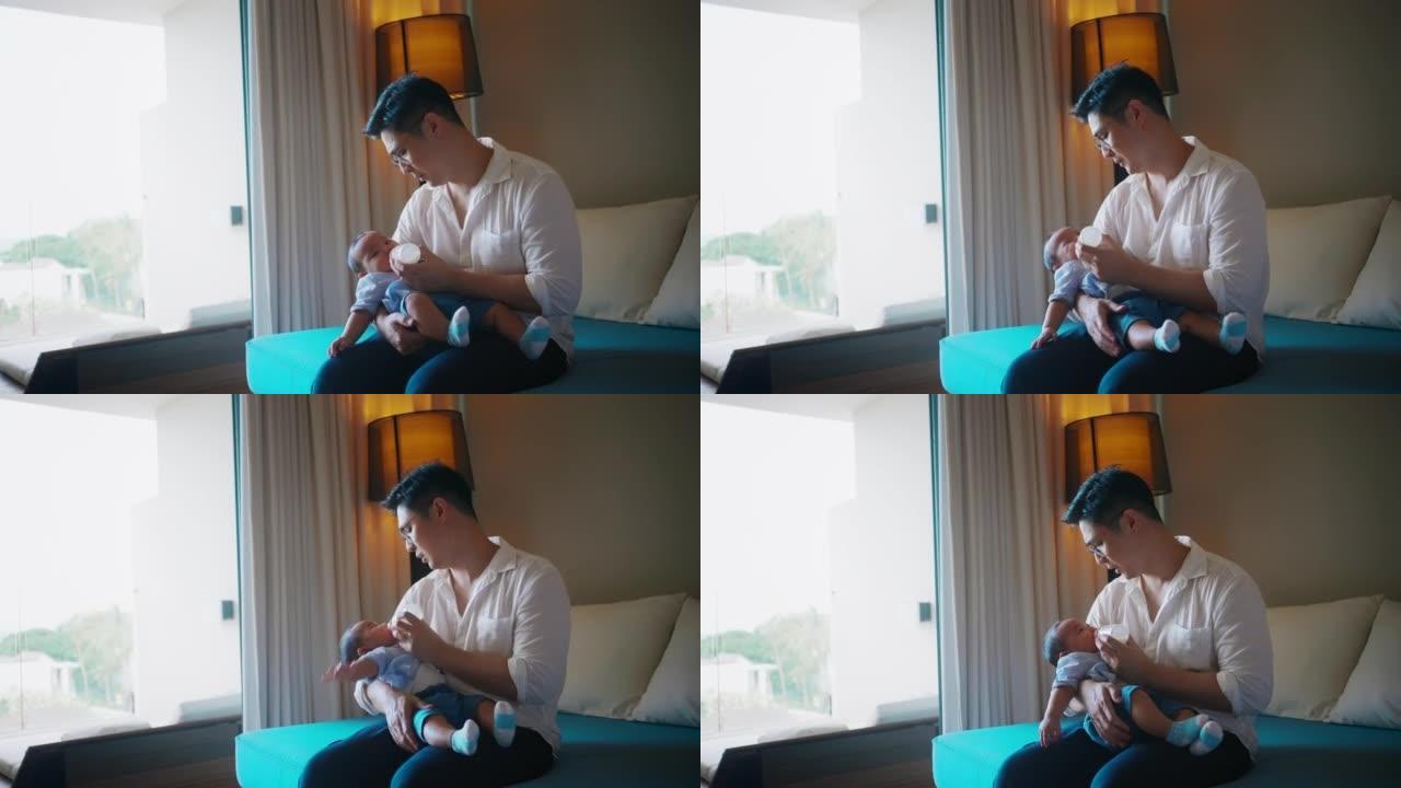 亚洲单身父亲从沙发上的婴儿奶瓶给婴儿喂奶。与新生儿成为父亲的时刻。