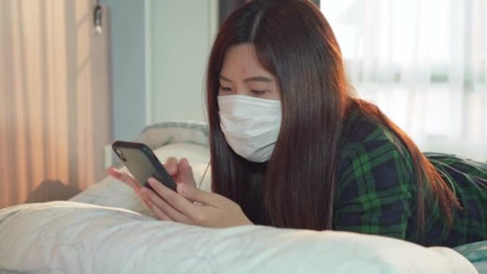 亚洲女性在床上使用智能手机为冠状病毒检疫