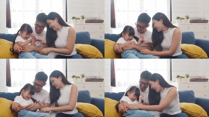 快乐快乐的亚洲家庭爸爸、妈妈和女儿在家里过生日时拥抱在沙发上玩耍。
