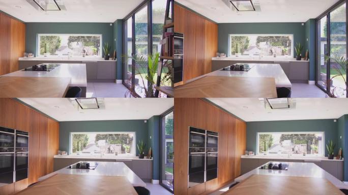 相机跟踪美丽的当代厨房的内部，配有合适的电器和储物空间，可以看到慢动作拍摄的花园景色