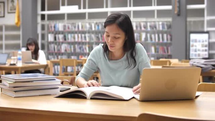 专注于亚洲女性的年轻学生在图书馆读书