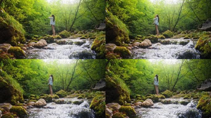 SLO MO年轻女子在森林中的溪流中享受新鲜的空气与和平