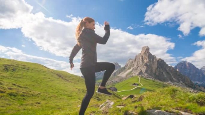 适合女运动员在山腰的绿色草地上跑步，停在边缘，欣赏美景