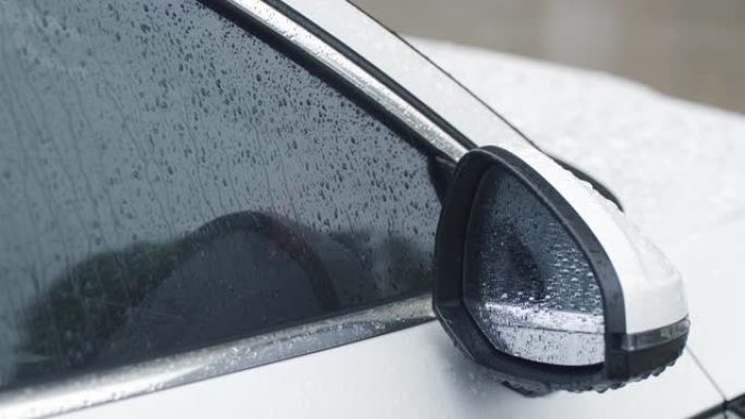 下雨天的特写车雨水滴落在窗上后视镜车头小