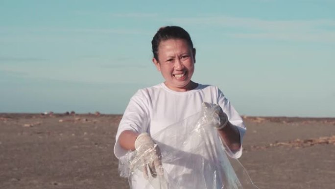 微笑的女人用塑料清洁海滩