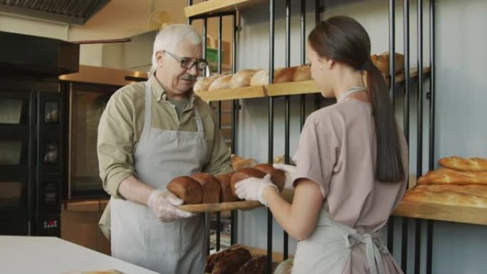 面包店员工将新鲜面包放在架子上