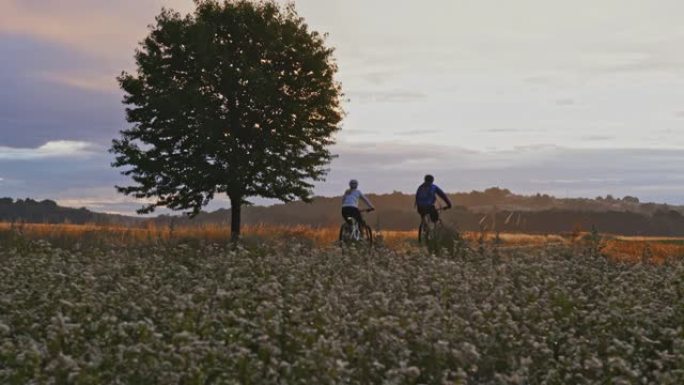SLO MO夫妇在黄昏时在乡间小路上骑自行车