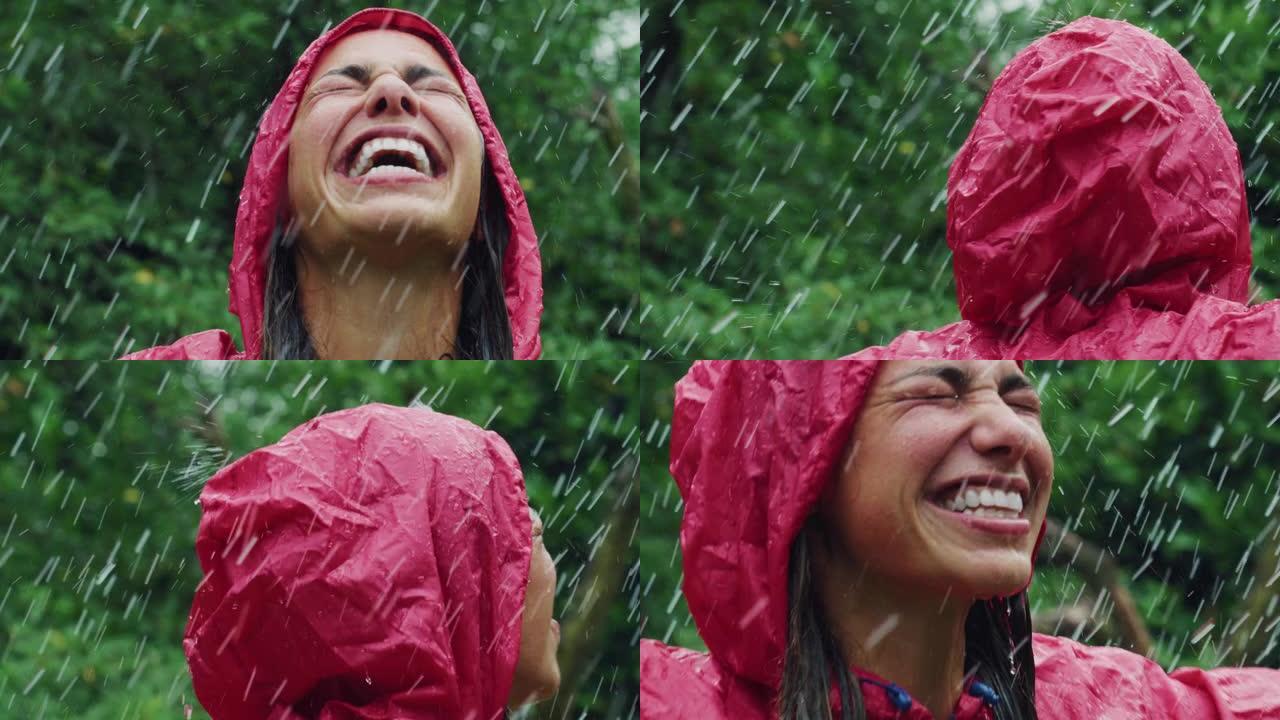 一个穿着红色雨衣的快乐女人的肖像，笑着享受在雨下。女性成年人感激水和自然的祝福，周围是树木。她在享受