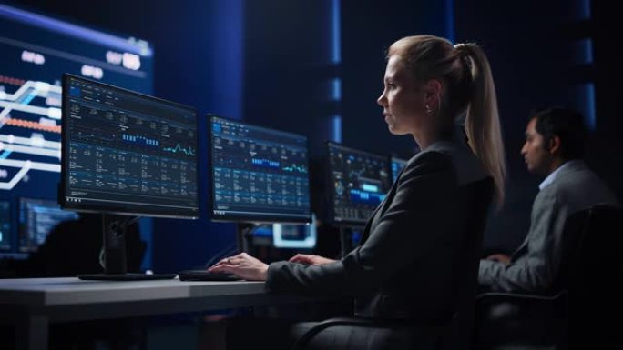 自信的女性数据科学家在大型基础设施控制室的个人计算机上工作。股市女性专家使用计算机显示图表，图表，信