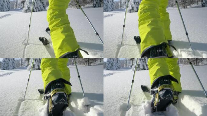 低角度: 无法识别的男性分裂者在闪闪发光的白雪皑皑的草地上远足。