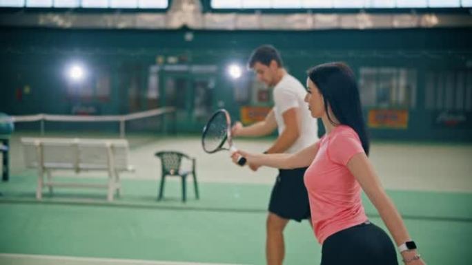 年轻的男教练在球场上教女子网球