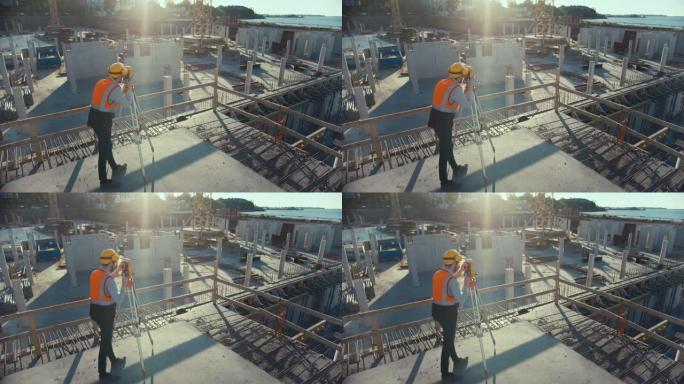 建筑工人使用经纬仪测量光学仪器测量建筑工地上水平和垂直平面的角度。戴着安全帽的工人为建筑物做投影。