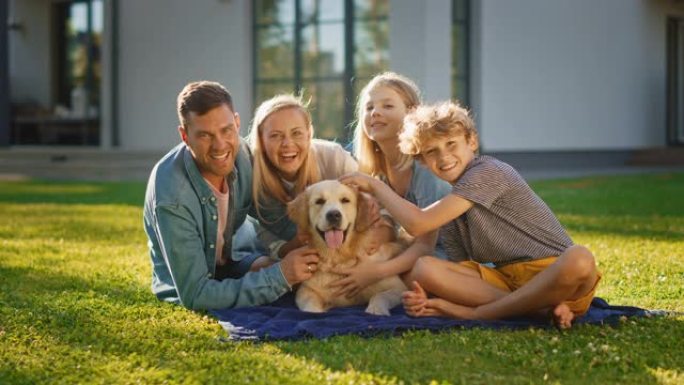 微笑的四口之家在草坪上野餐，与快乐的金毛猎犬合影。田园诗般的家庭在避暑别墅后院与忠诚的血统狗在户外玩