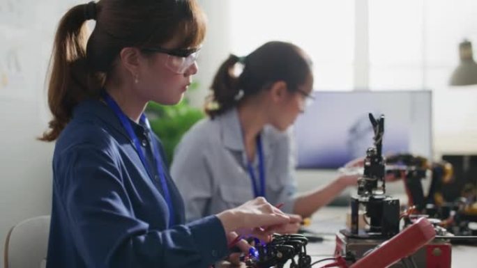 工程师在控制室测试机器人手。女性在做她的机器人项目，她测试传感器信号。技术与创新理念