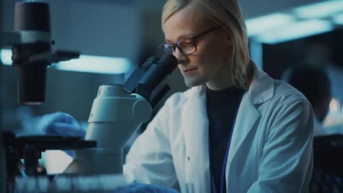 女性研究科学家使用微量移液管在显微镜载玻片上提取样品，并在现代实验室的示波器下观察。科学家在技术和计