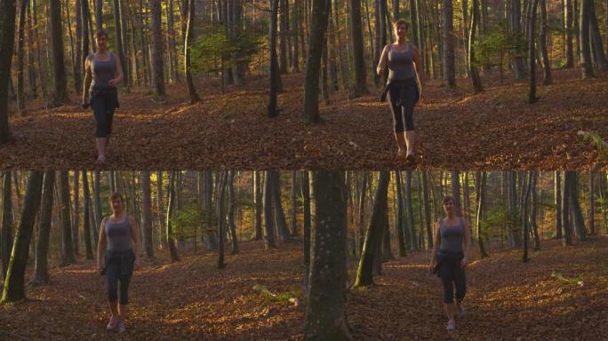肖像快乐的年轻女子在秋天的彩色森林中沿着风景优美的小径行走