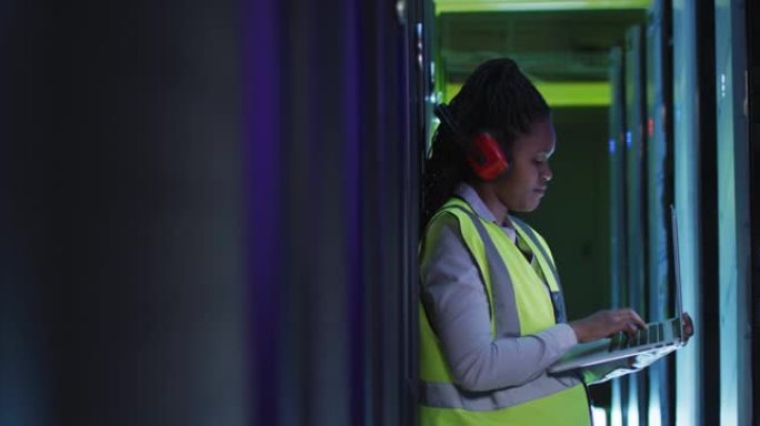 非裔美国女计算机技术员使用笔记本电脑在商务服务器机房工作