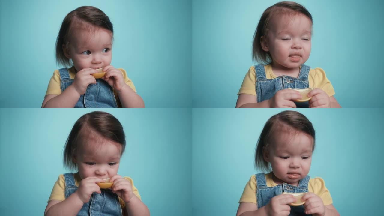 一个可爱的漂亮婴儿在吃柠檬。一个孩子品尝生柠檬。顽皮的小女孩吃水果。抱着吃的美味的小孩。有趣的表达情