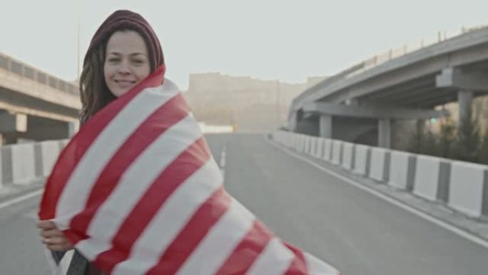 带着美国国旗的女人在高速公路上对着镜头微笑