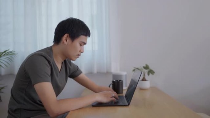 亚洲残疾人在家中使用笔记本电脑工作。