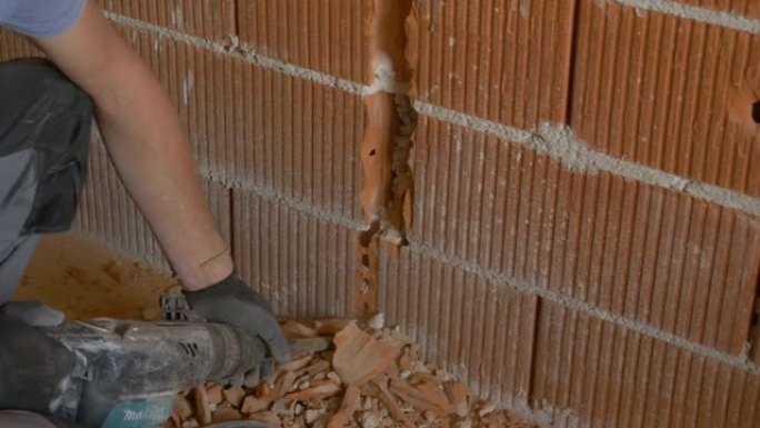 特写: 工人在公用事业安装过程中使用手提钻压碎砖墙