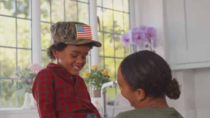 在厨房里，休假的美军母亲和戴着军装帽的儿子玩耍的特写镜头——慢镜头