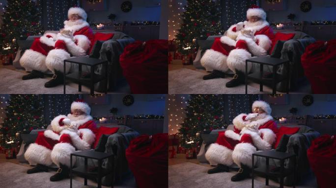 圣诞老人坐在装饰精美的客厅里过圣诞节，坐在灰色的沙发上看电视，吃着爆米花。圣诞老人正在仔细地观看电视