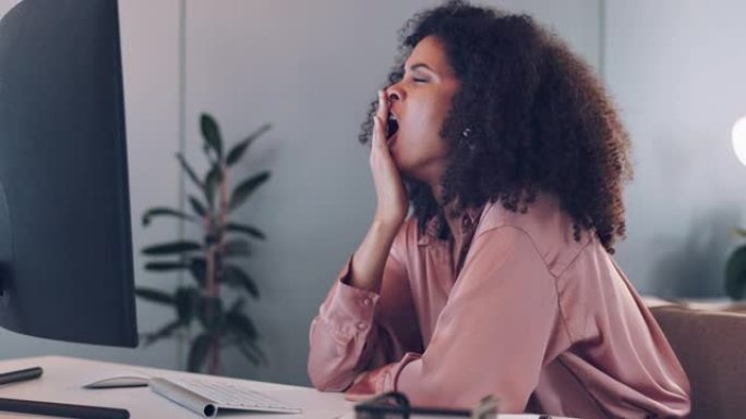 商业女性，在办公桌前用电脑和过度工作，疲劳和加班的焦点问题。黑人妇女打着哈欠，精疲力竭，员工用技术为