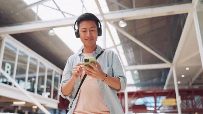 电话，音乐耳机和亚洲男子在购物中心流媒体播客或广播中行走。技术，旅行和快乐的男性在城市建筑中的移动智