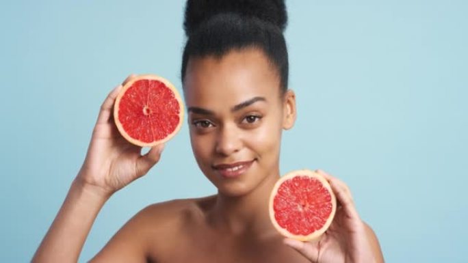 黑人妇女，美容和护肤微笑与葡萄柚在蓝色工作室背景下。健康饮食中的快乐非洲女性模特肖像，为皮肤，面部和