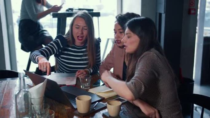 全女性团队合作概念。三个美丽多样的商业伙伴使用笔记本电脑在咖啡店一起工作。