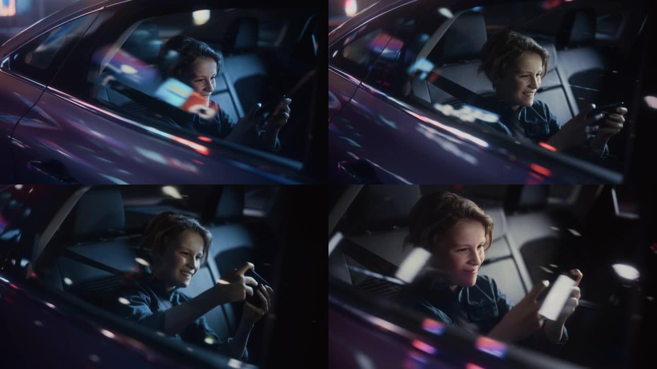 英俊的小男孩坐在汽车后座上，晚上通勤回家。乘客在智能手机上玩视频游戏，而在城市街道的出租车上，霓虹灯