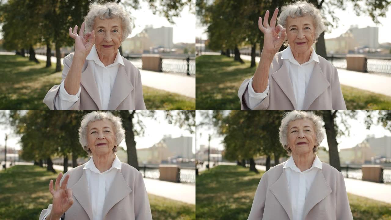积极的高级女性肖像在城市街道上表现出良好的手势并在户外微笑