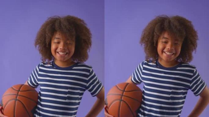 男孩在紫色工作室背景下拿着篮球的垂直视频-慢动作拍摄