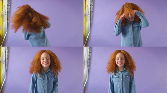 演播室拍摄的红发女孩旋转并在紫色背景下大笑-慢动作拍摄