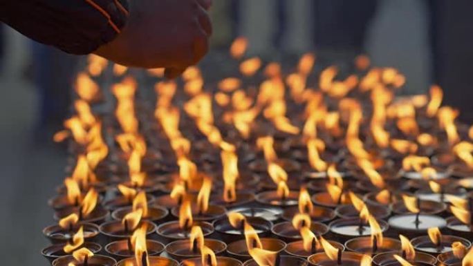 男人在蜡烛上祈祷温暖他的手。在佛教圣地博德哈纳斯，祈祷的手和燃烧的蜡烛。加德满都,尼泊尔。慢镜头