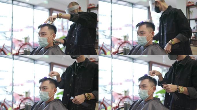 穿着防护服的亚洲华人发型师在发廊为他的顾客理发