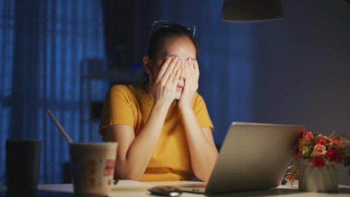 年轻的女商人在晚上使用计算机时看起来压力很大