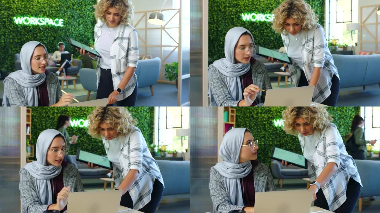 有创意的穆斯林雇员在办公室的笔记本电脑上与经理谈论公司项目。商业，专业和市场营销女性咨询领导者的数据