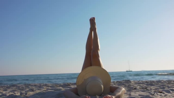 撒丁岛海滩上戴帽子的女人的慢动作视图。