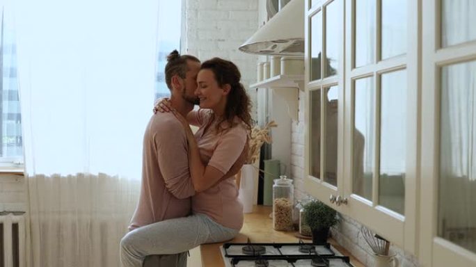 浪漫美丽的年轻夫妇在厨房激情接吻。