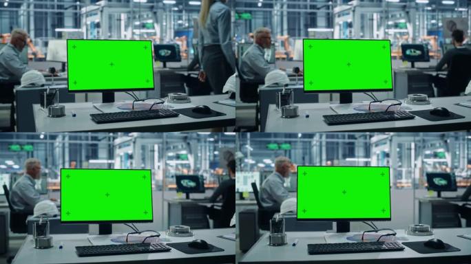 汽车厂: 桌上绿屏色度钥匙电脑。背景技术不同的工程师团队在自动化机械臂装配线制造车辆办公室工作